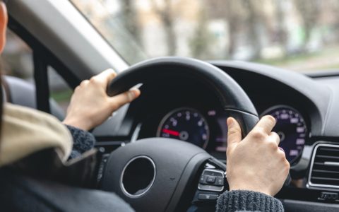 A woman is driving a car, a woman is driving in a car at speed.