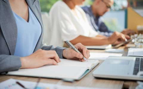 Cropped image of business lady writing her ideas in notepad